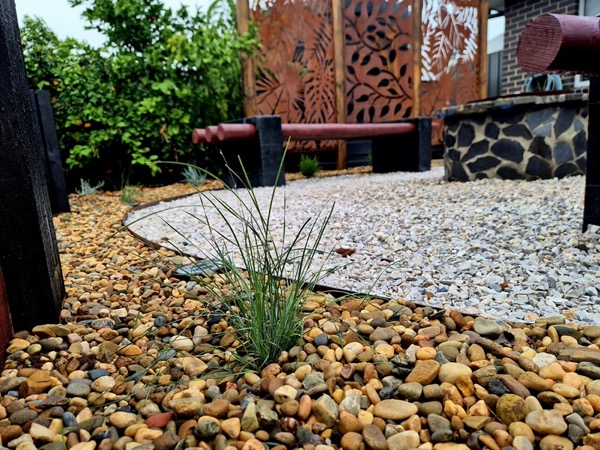 A pebble garden bed and feature screen by MR Landscapes