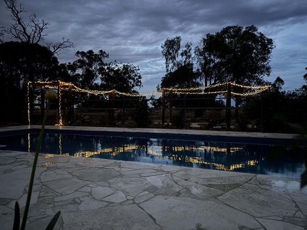 A pool and firepit area lit at dusk by MR Landscapes