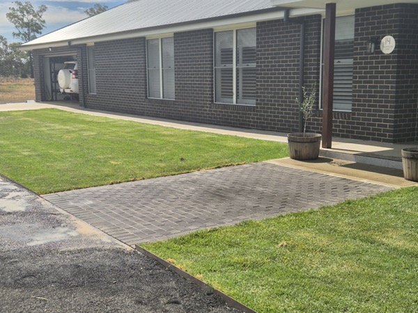 A new lawn and paved path beside a home by MR Landscapes