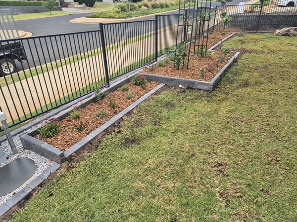 A fence line, garden bed and lawn by MR Landscapes
