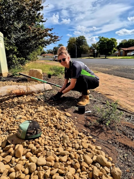 Matt from MR Landscapes planting natives in a pebble garden bed by a Dubbo footpath
